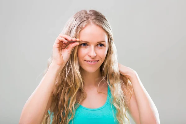 Hermosa mujer usando pinzas — Foto de Stock