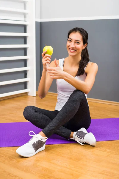 Fitness donna mangiare mela e mostrando pollice in su — Foto Stock