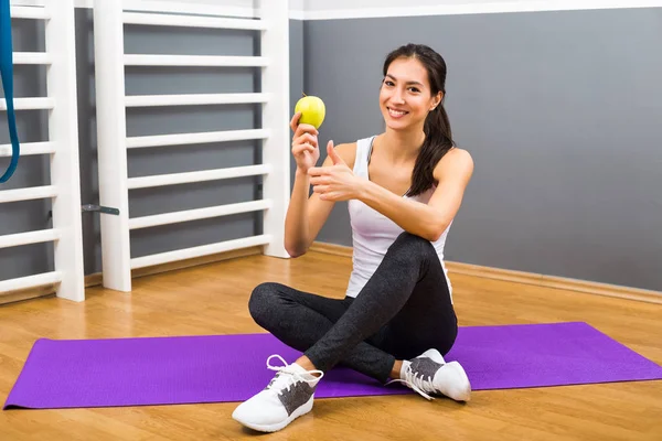 Fitness mujer comiendo manzana y mostrando el pulgar hacia arriba —  Fotos de Stock