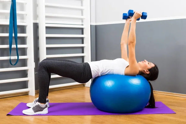 Mujer fitness practicando con pesas y pilates pelota — Foto de Stock