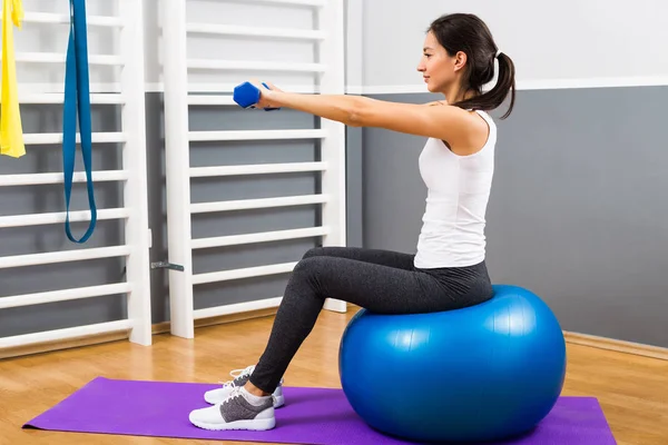 Fitness-Frau übt mit Hanteln und Pilates-Ball — Stockfoto