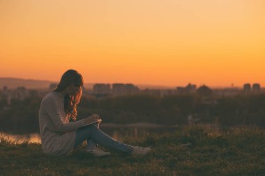 Gün batımında notlar yazma kadın