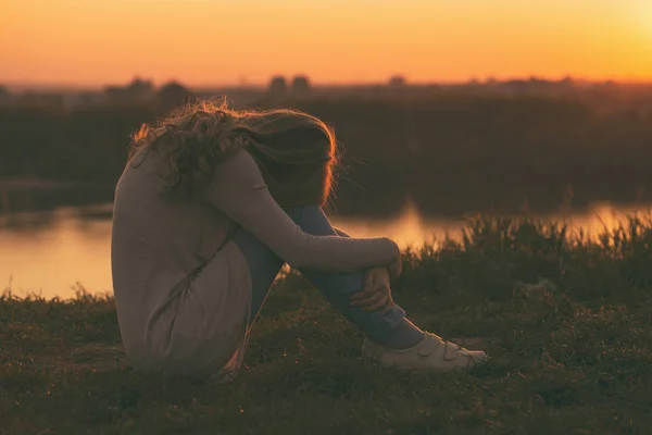 Treurige vrouw bij de zonsondergang — Stockfoto