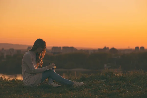Woman writing notes at the sunset — Stock Photo, Image