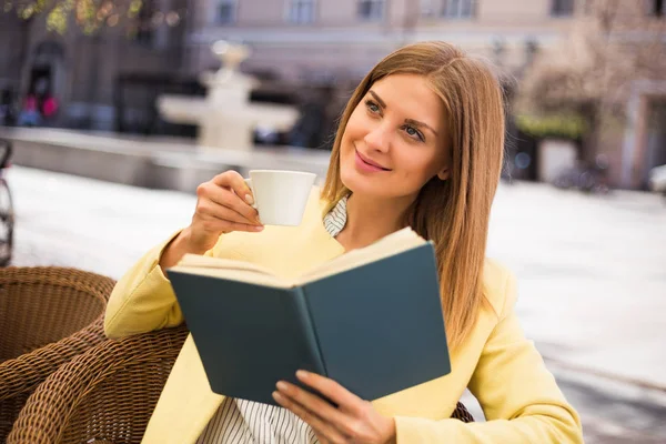 Kadın kahve içiyor ve kitap okuyor. — Stok fotoğraf