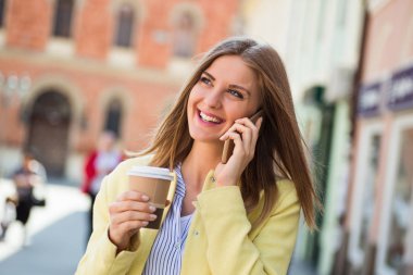 Kadın cep telefonu kullanıyor ve kahve içiyor. 