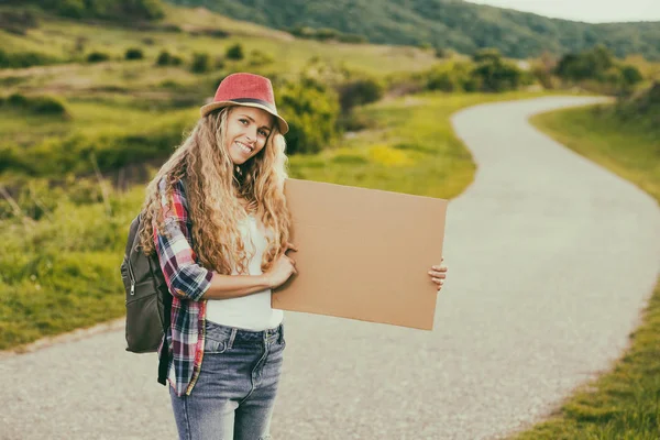 Mujer sosteniendo cartón en blanco y autostop en el país — Foto de Stock