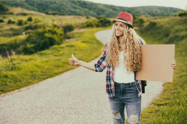 Mujer sosteniendo cartón en blanco y autostop en el país —  Fotos de Stock