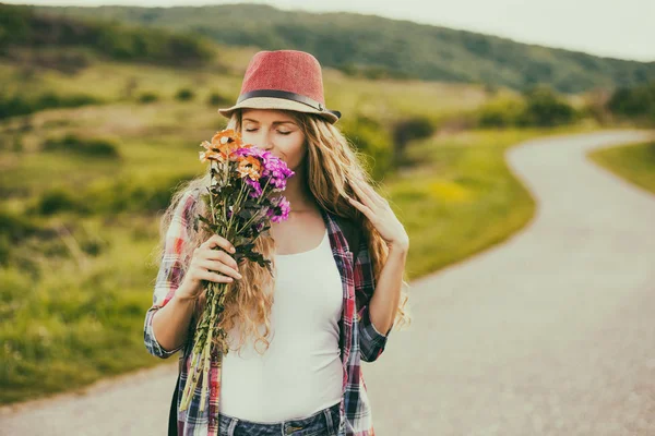 Kvinna att lukta bukett blommor på landet — Stockfoto