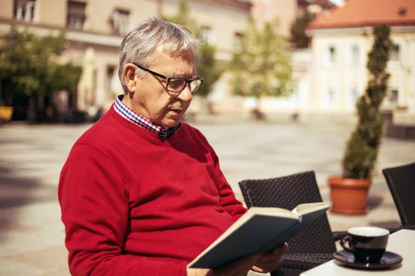 Homme âgé lisant un livre et buvant du café — Photo