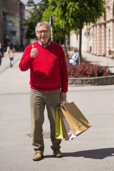 Hombre mayor mostrando el pulgar hacia arriba mientras hace compras — Foto de Stock