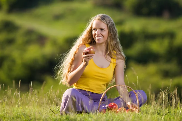 Женщина ест яблоко на лугу — стоковое фото