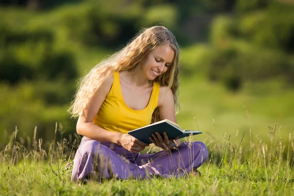 Frau liest Buch auf der Wiese — Stockfoto