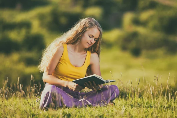 Frau liest Buch auf der Wiese — Stockfoto