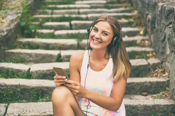 Cep telefonu kullanan kulaklıklı genç bir kadın.