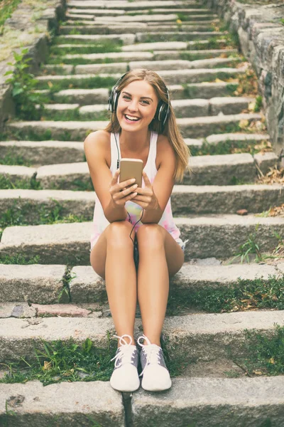 Młoda kobieta ze słuchawkami z telefonu komórkowego — Zdjęcie stockowe