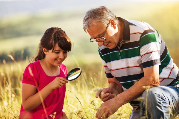 Abuelo y nieta exploran la naturaleza con lupa — Foto de Stock