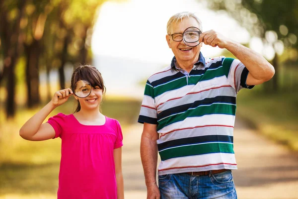 Abuelo y nieta mirando a través de lupa — Foto de Stock