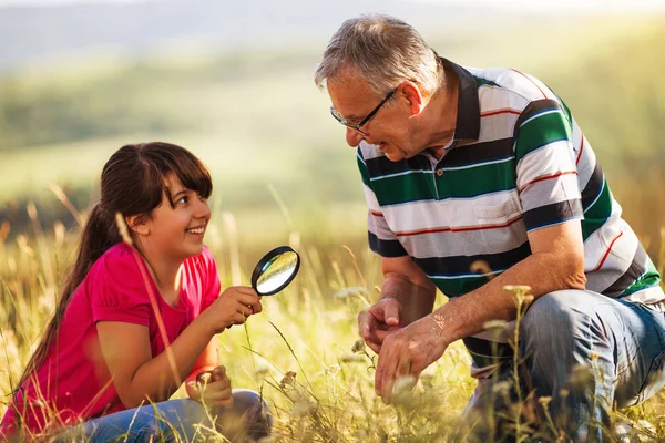 Grandfather and granddaughter explore nature with magnifying glass — Stock Photo, Image