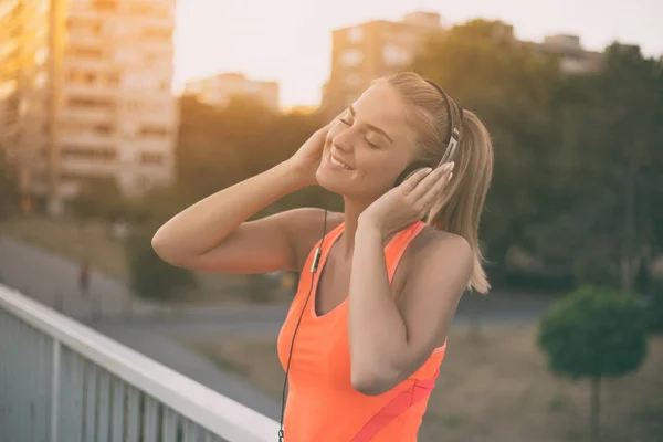 Sportiga kvinnan lyssnar musik — Stockfoto