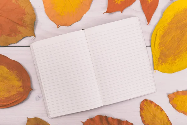 Notizbuch auf Holztisch mit bemalten Blättern — Stockfoto