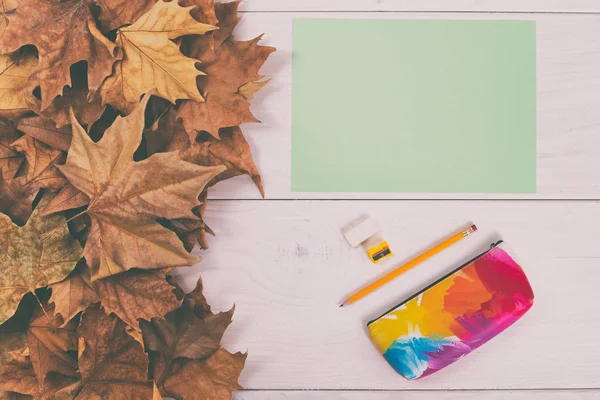 Livre vert et fournitures scolaires sur table en bois avec feuilles d'automne — Photo