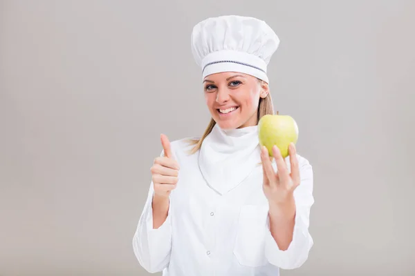 Žena kuchař ukazuje palcem a apple — Stock fotografie