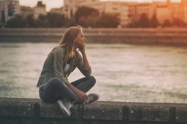 Kvinna sitter vid åstranden — Stockfoto