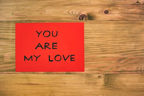 Red paper with message you are my love on wooden table.Image is intentionally toned.