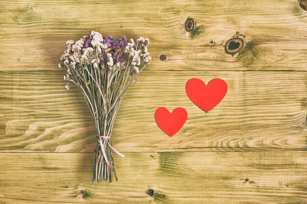 在木桌上的花朵与心形的花束 图像是故意色调 — 图库照片