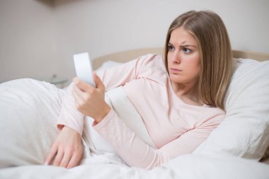 Çalar saat yatakta tutan pijama kızgın kadın.