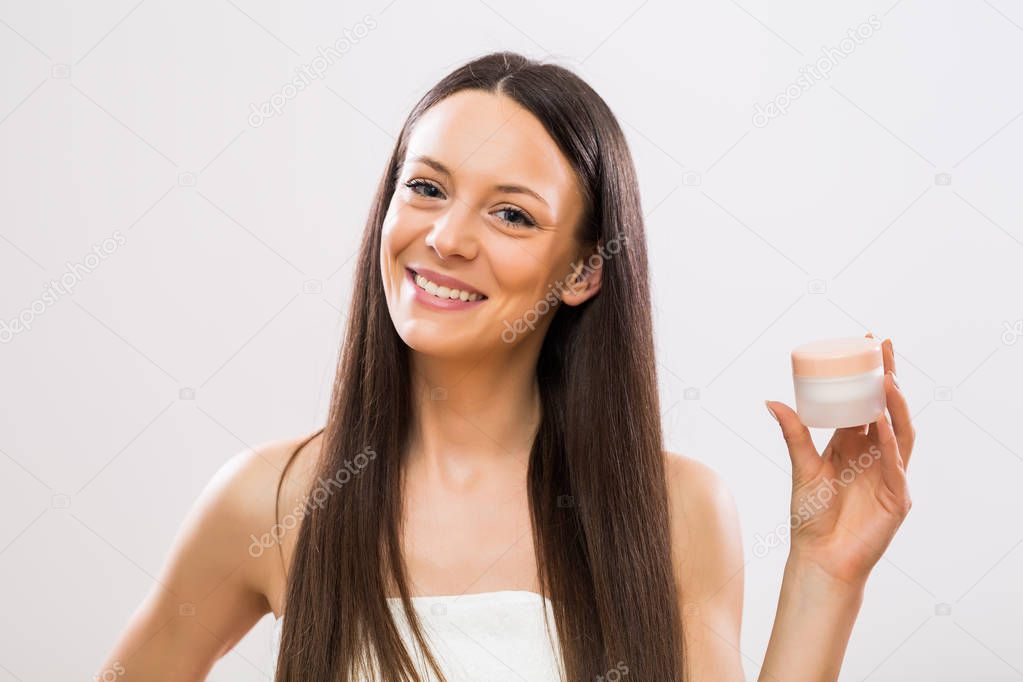 Portrait of  beautiful brunette woman showing beauty product.