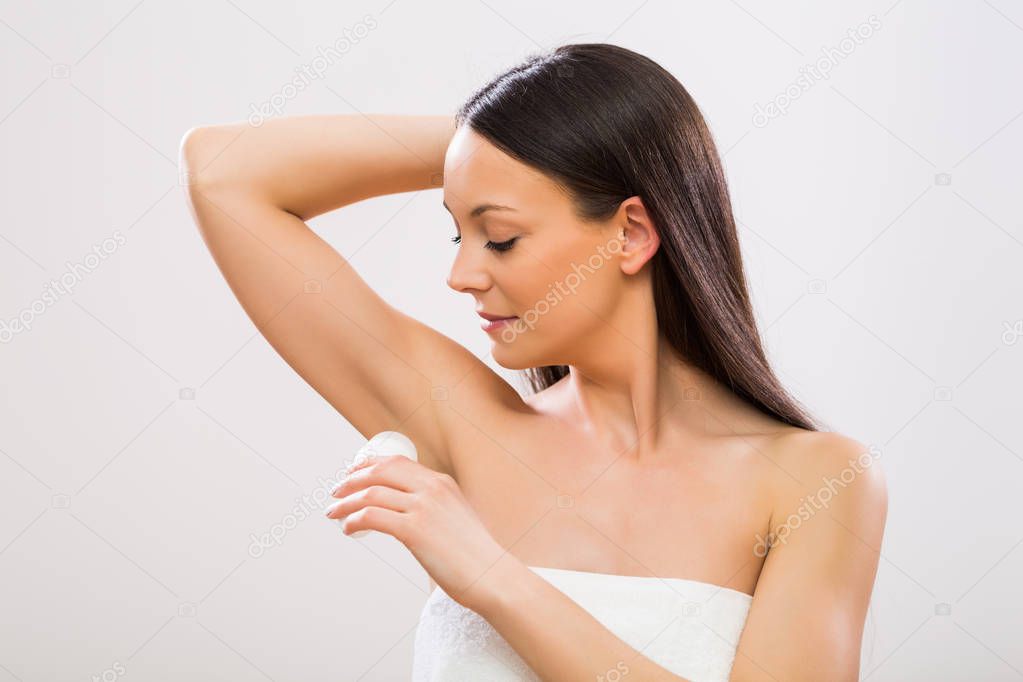 Beautiful woman using antiperspirant.