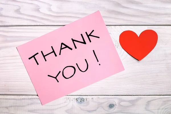 Text thank you with heart shape on wooden table.Image is intentionally toned.