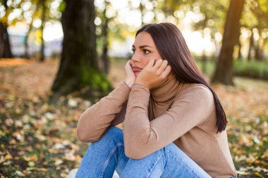 Üzgün kadın parkta tek başına oturuyor..