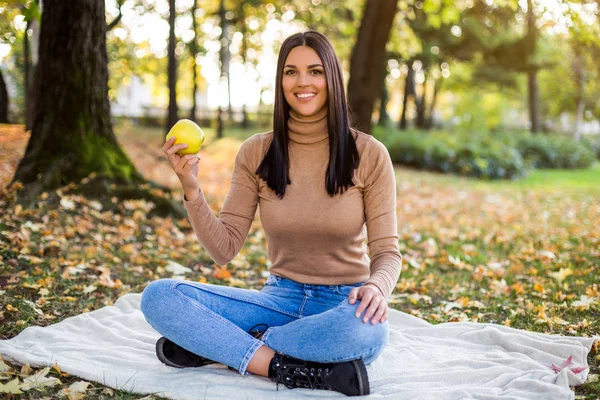 秋を楽しんで公園で休んでいる間にリンゴを食べる美しい女性 — ストック写真