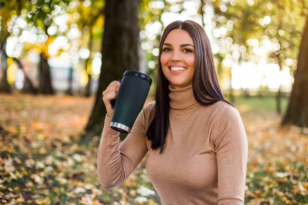 公園で秋を楽しみながらコーヒーを飲む美しい女性 — ストック写真