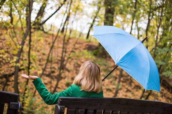 Mulher Segurando Guarda Chuva Azul Verificando Chuva Enquanto Sentado Parque — Fotografia de Stock