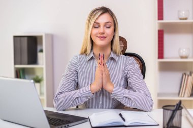 İş kadını çalışırken ofisinde meditasyon yapıyor..