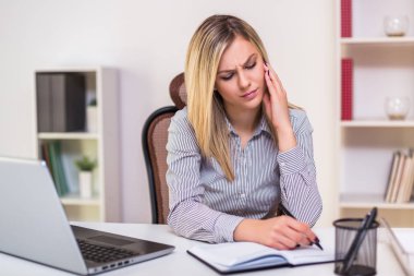 İş kadını ofisinde çalışırken baş ağrısı çekiyor..