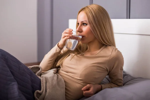 Vakker Kvinne Som Drikker Vann Når Hun Ligger Sengen – stockfoto