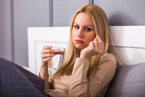 Tråkig Kvinna Dricker Piller När Hon Sitter Sängen Sitt Sovrum — Stockfoto
