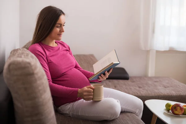 Vacker Gravid Kvinna Njuter Att Läsa Bok Och Dricka Hemma — Stockfoto