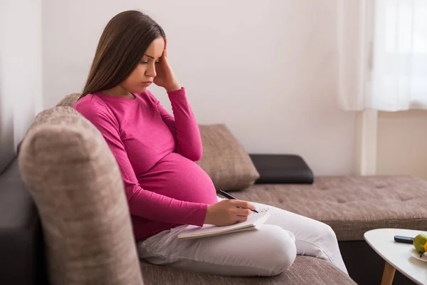 Preocupada Mujer Embarazada Escribiendo Para Hacer Una Lista Cuaderno Mientras — Foto de Stock