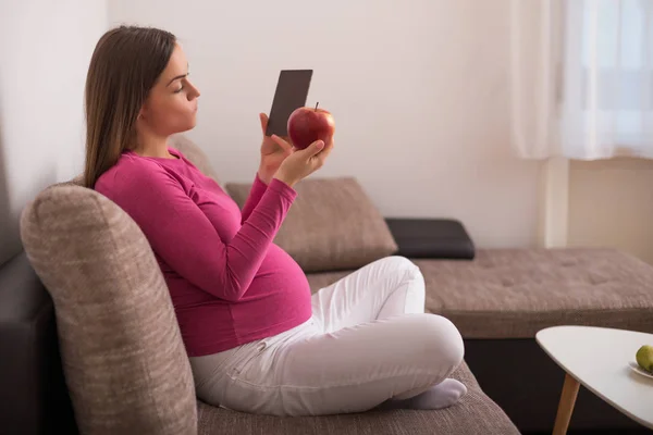 妊娠中の女性は何を食べるかを決定しようとしています アップルやチョコレート — ストック写真