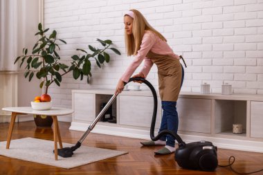 Güzel ev hanımı evini elektrikli süpürgeyle temizliyor..