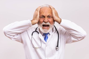 Gri arka planda çok çalışan kıdemli doktorun resmi.