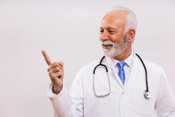 Retrato Del Médico Senior Apuntando Sobre Fondo Gris —  Fotos de Stock