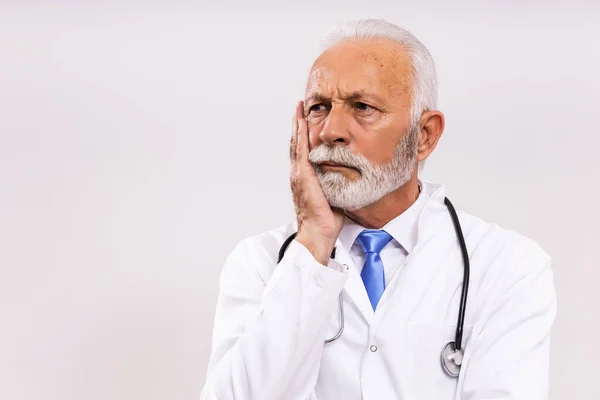 Image of worried  senior doctor thinking on gray background.