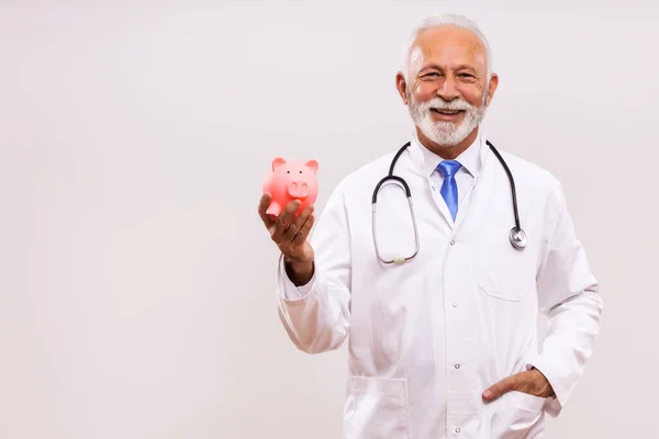 Retrato Del Médico Senior Sosteniendo Alcancía Sobre Fondo Gris —  Fotos de Stock